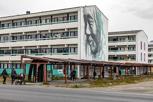 HABITANTS SE PROMENANT DEVANT UNE CITE HLM PEINTE AVEC LE PORTRAIT D'UN INUIT, NUUK, GROENLAND, DANEMARK 