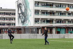 JEUNES JOUANT AU FOOTBALL DEVANT UNE CITE HLM PEINTE AVEC LE PORTRAIT D'UN INUIT, NUUK, GROENLAND, DANEMARK 