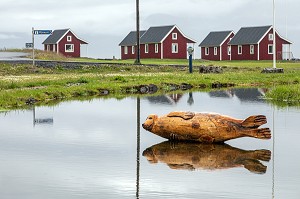 SCULPTURE DE PHOQUE EN BOIS DEVANT LES PETITES MAISONS ROUGES DE L'HOTEL DE CHARME FEROABJONUSTAN MJOEYRI AU BORD DU FJORD, ESKIFJORDUR, ISLANDE, EUROPE 