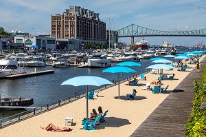 BAIN DE SOLEIL SUR LA PLAGE D'ETE SUR LE BASSIN DE L'HORLOGE, PORT DE PLAISANCE ET PONT JACQUES CARTIER, MONTREAL, QUEBEC, CANADA 