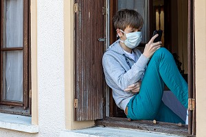 ADOLESCENT AVEC SON MASQUE DE PROTECTION SUR LA FENETRE DE SA MAISON, MESURES SANITAIRES DE PREVENTION, CONFINEMENT SUITE A L'EPIDEMIE DE CORONAVIRUS, RUGLES, NORMANDIE, FRANCE 