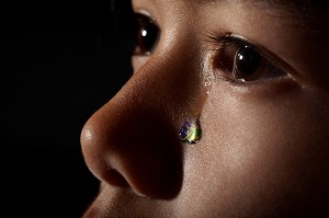 MELANCOLIE, PETITE FILLE D'ORIGINE ASIATIQUE PLEURANT LA TERRE DISPARUE, ILLUSTRATION DU SOUVENIR DE NOTRE PLANETE COMME SON REFLET DANS LA LARME DE L'ENFANT, EXPOSITION PHOTOGRAPHIQUE ‘TERRE FRAGILE’ MONTRANT L’IMPACT DE L’HOMME SUR LA PLANETE, FRANCE, MONDE 