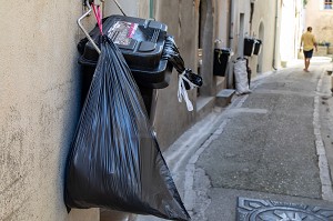 POUBELLES ACCROCHEES AUX MURS DANS LES RUES, ANIANE, HERAULT, OCCITANIE, FRANCE 