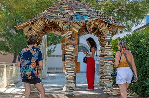 LECTEURS DE PASSAGE DEVANT UNE BOITE A LIVRES D'OCCASION, KIOSQUE D'ECHANGE CONSTRUIT EN LIVRES, ANIANE, HERAULT, OCCITANIE, FRANCE 