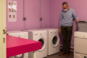 RESIDENT DANS LA BUANDERIE POUR LAVER SON LINGE, FOYER D'HEBERGEMENT POUR ADULTES EN SITUATION DE HANDICAP INTELLECTUEL, RESIDENCE LA CHARENTONNE, ADAPEI27, ASSOCIATION DEPARTEMENTALE D'AMIS ET DE PARENTS, BERNAY, EURE, NORMANDIE, FRANCE 