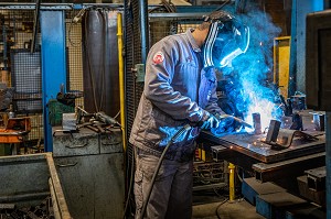 POSTE DE SOUDURE, OUVRIER SOUDEUR AU TRAVAIL POUR L'ASSEMBLAGE DE PIECES METALLIQUES DANS SON USINE, L'AIGLE, ORNE, NORMANDIE, FRANCE 