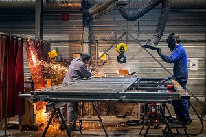 POSTE DE SOUDURE, OUVRIER SOUDEUR AU TRAVAIL POUR MEULAGE DE PIECES METALLIQUES DANS SON USINE, L'AIGLE, ORNE, NORMANDIE, FRANCE 