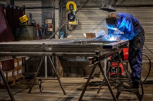 POSTE DE SOUDURE, OUVRIER SOUDEUR AU TRAVAIL POUR L'ASSEMBLAGE DE PIECES METALLIQUES DANS SON USINE, L'AIGLE, ORNE, NORMANDIE, FRANCE 