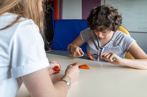 SEANCE D'ERGOTHERAPIE AVEC UN RESIDENT POUR APPRENDRE A TENIR SES COUVERTS A TABLE, SESSAD LA RENCONTRE, ACCUEIL DE JOUR, ORGANISME DE SOUTIEN ET DE SERVICES AUX PERSONNES HANDICAPEES, LE NEUBOURG, EURE, NORMANDIE, FRANCE 