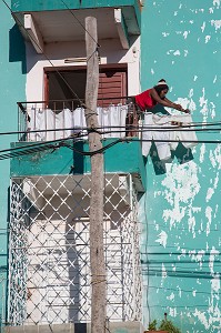 FEMME CUBAINE ETENDANT SON LINGE SUR UNE FACADE COLOREE DECREPIE, TRINIDAD, CLASSEE AU PATRIMOINE MONDIAL DE L’HUMANITE PAR L’UNESCO, CUBA, CARAIBES 