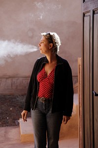 LOI CONTRE LE TABAGISME, FEMME FUMANT DEHORS, SUR LE PAS DE SA PORTE 