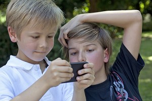 ENFANTS JOUANT A DES JEUX VIDEOS SUR LE TELEPHONE PORTABLE DES PARENTS, FRANCE 