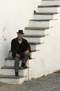 ANCIEN POSE SUR LES MARCHES DE SA MAISON DANS LE VILLAGE FORTIFIE DE MONSARAZ, ALENTEJO, PORTUGAL 