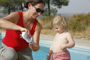 MERE ETALE DE LA CREME SOLAIRE POUR PROTEGER LA PEAU DE SON ENFANT DES RAYONS DU SOLEIL 