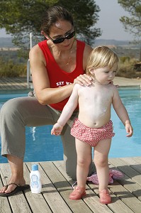 MERE ETALE DE LA CREME SOLAIRE POUR PROTEGER LA PEAU DE SON ENFANT DES RAYONS DU SOLEIL 