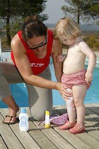 MERE ETALE DE LA CREME SOLAIRE POUR PROTEGER LA PEAU DE SON ENFANT DES RAYONS DU SOLEIL 