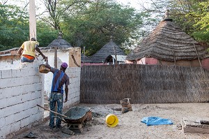 CONSTRUCTION D'UN MUR DEVANT LES CASES AU TOIT DE PAILLE, VILLAGE PEUL DE GUELAKH, SENEGAL, AFRIQUE DE L'OUEST 
