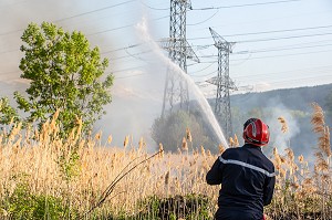 SAPEUR-POMPIER EN TRAIN D'ETEINDRE UN FEU DE BROUSSAILLES (ROSEAUX) SOUS DES PYLONES DE LIGNES A HAUTE TENSION, SAPEURS-POMPIERS PRINCIPAL DU CENTRE DE SECOURS DE CHAMBERY, LES MARCHES, SAVOIE (73), FRANCE 