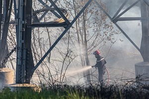 SAPEUR-POMPIER EN TRAIN D'ETEINDRE UN FEU DE BROUSSAILLES SOUS DES PYLONES DE LIGNES A HAUTE TENSION, SAPEURS-POMPIERS PRINCIPAL DU CENTRE DE SECOURS DE CHAMBERY, LES MARCHES, SAVOIE (73), FRANCE 