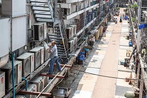 OUVRIER AU TRAVAIL SUR UNE FACADE D'IMMEUBLE AVEC DES APPARTEMENTS EQUIPES D'UNE CLIMATISATION, BANGKOK, THAILANDE, ASIE 