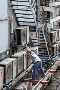 OUVRIER AU TRAVAIL SUR UNE FACADE D'IMMEUBLE AVEC DES APPARTEMENTS EQUIPES D'UNE CLIMATISATION, BANGKOK, THAILANDE, ASIE 