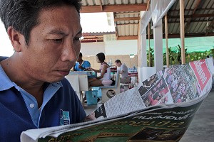 HOMME LISANT SON JOURNAL, CHUMPHON, THAILANDE 