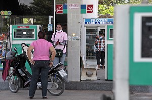 POMPISTE AVEC SON MASQUE DE PROTECTION A LA STATION SERVICE, BANG SAPHAN, THAILANDE, ASIE 