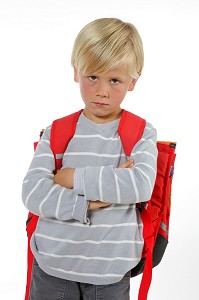 ECOLIER MECONTENT AVEC SON CARTABLE LE JOUR DE LA RENTREE DES CLASSES 