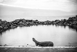 PIED ET JAMBE D'UN TOURISTE DERRIERE UN MURET DEVANT LA MER, CANICO, MADERE, PORTUGAL 