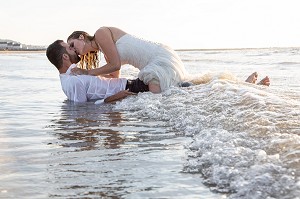 BISOUS TENDRES D'UN COUPLE DE MARIES DANS LA MER, MARIAGE TRASH THE DRESS, TROUVILLE-SUR-MER, NORMANDIE, FRANCE 